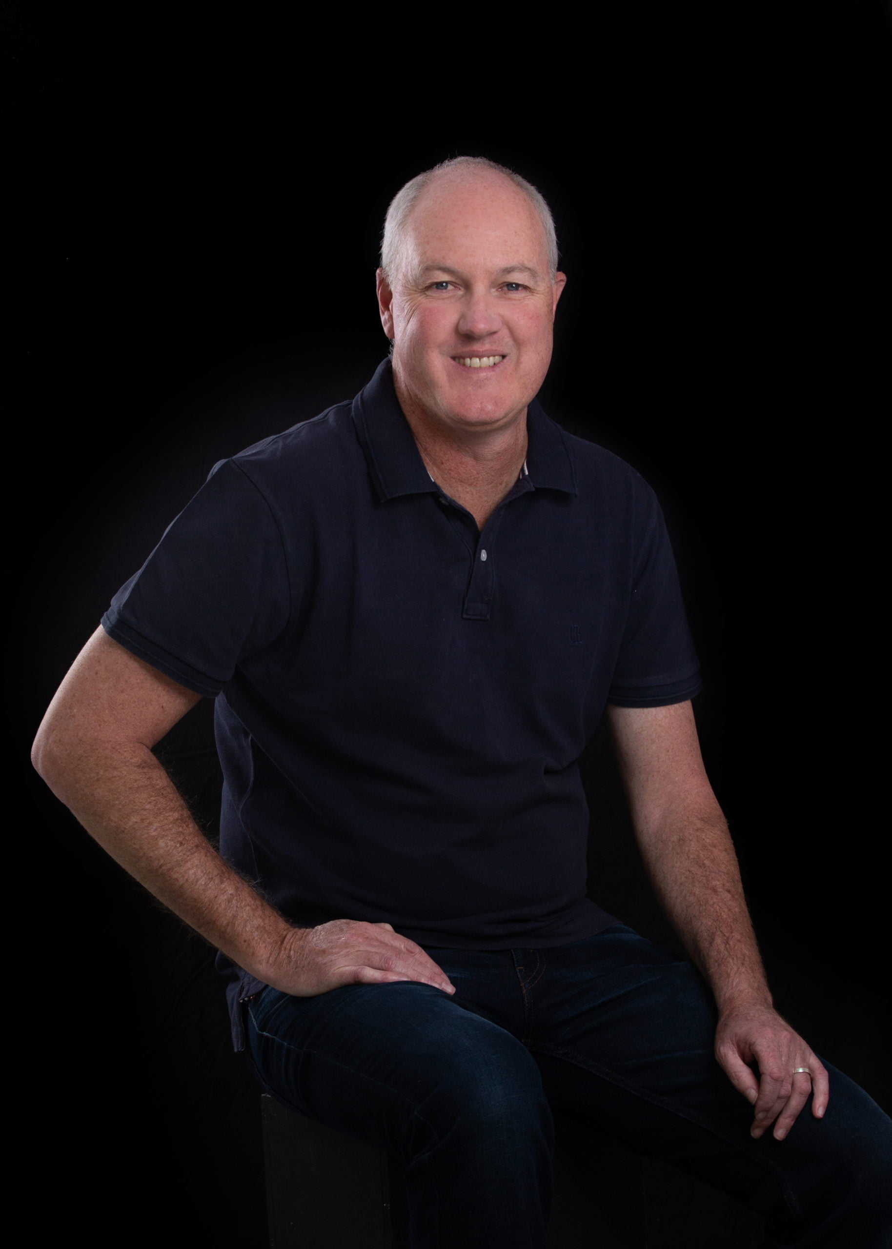 Garreth Ewing seated in a casual black golf shirt at a coaching event.